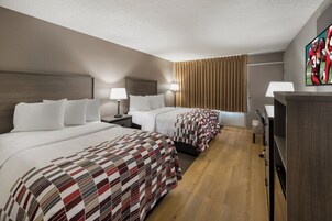Habitación de hotel con dos camas, piso de madera y televisor en la pared.
