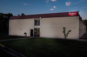 A Red Roof Inn building with a brick facade, a red roof, and a small front garden.