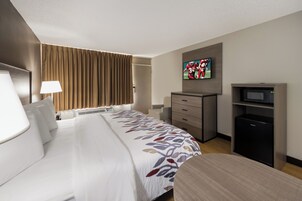 Habitación de hotel con cama, escritorio, televisor y minibar.
