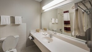 A bathroom with a white sink, mirror, and toilet. There are towels hanging on the wall and a shower curtain. - Red Roof Inn Dumfries - Quantico (Dumfries)
