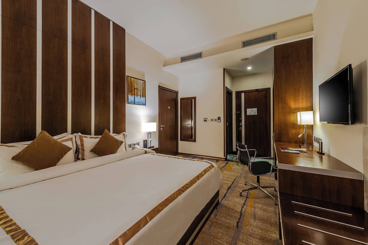 Une chambre d’hôtel avec un grand lit, un bureau, une chaise et un téléviseur.