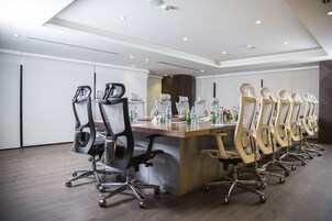 Un salón de conferencias con una larga mesa, varias sillas y un diseño moderno de techo.