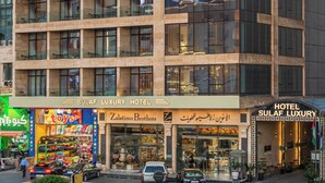 Een modern hotelgebouw met een opvallend bord waarop 'Sulaim Luxury Hotel' staat.
