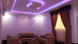 A modern living room with a sofa set, a coffee table, and a ceiling with recessed lighting and a circular design.