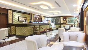 A hotel lobby with a reception desk, seating area, and decorative wall panels.