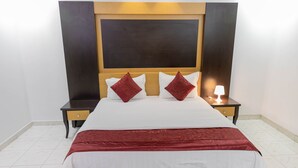 A hotel room with a large bed, two nightstands, a bedside lamp, and a wooden headboard.