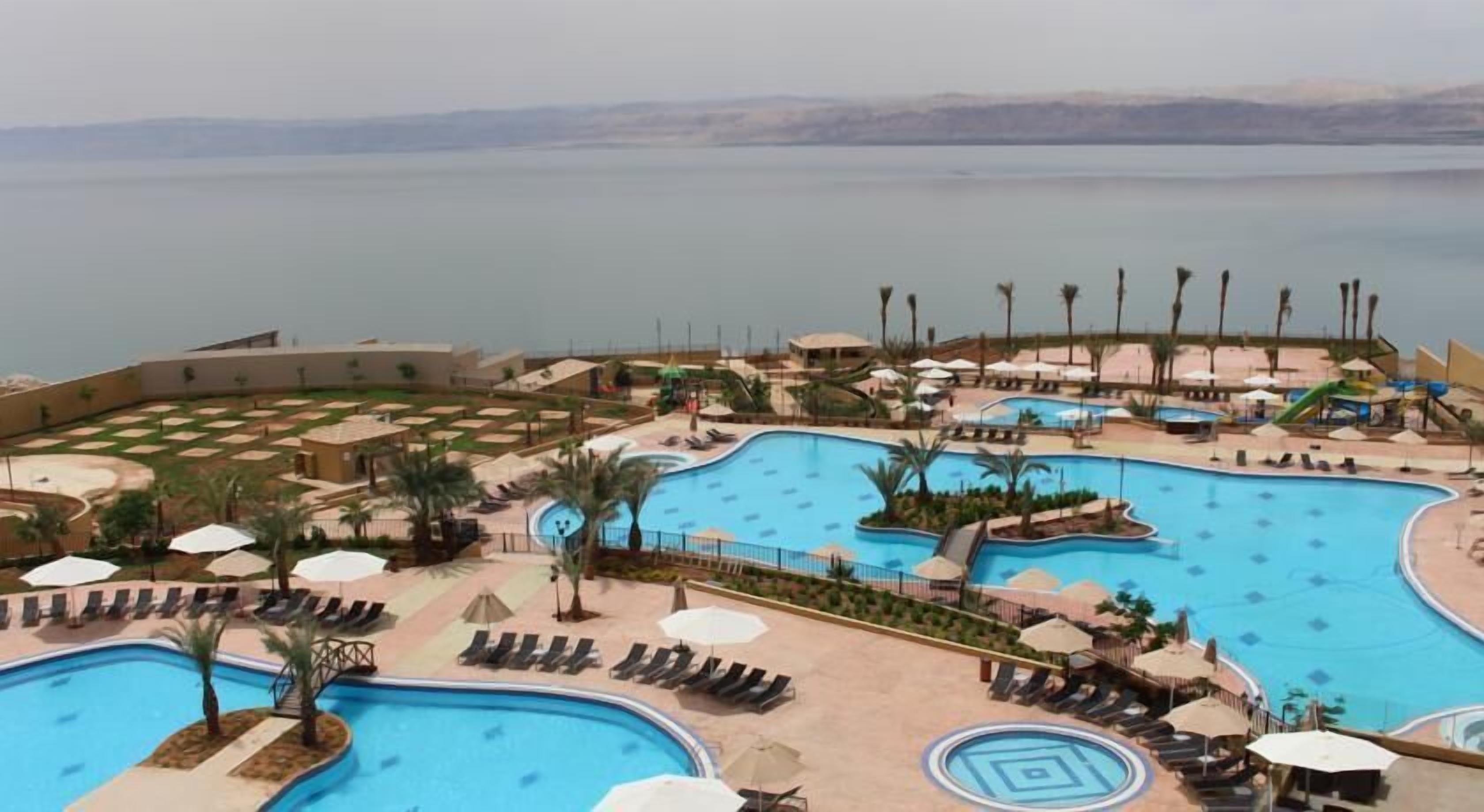 Un resort con varias piscinas, tumbonas y sombrillas.