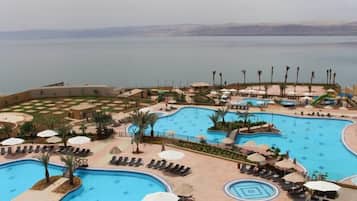 Un resort con varias piscinas, tumbonas y sombrillas.