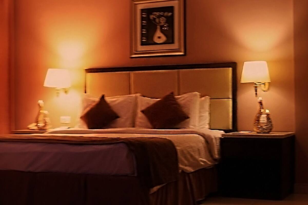 Een hotelkamer met een bed, twee bedlampen, een nachtkastje en een stoel.