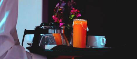 A tray with a glass of orange juice, a white mug, and a bottle of water.
