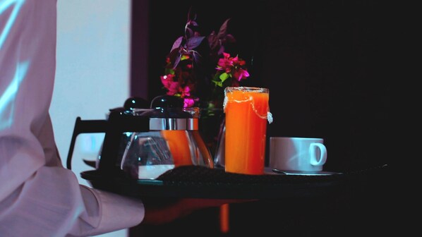A tray with a glass of orange juice, a white mug, and a bottle of water.