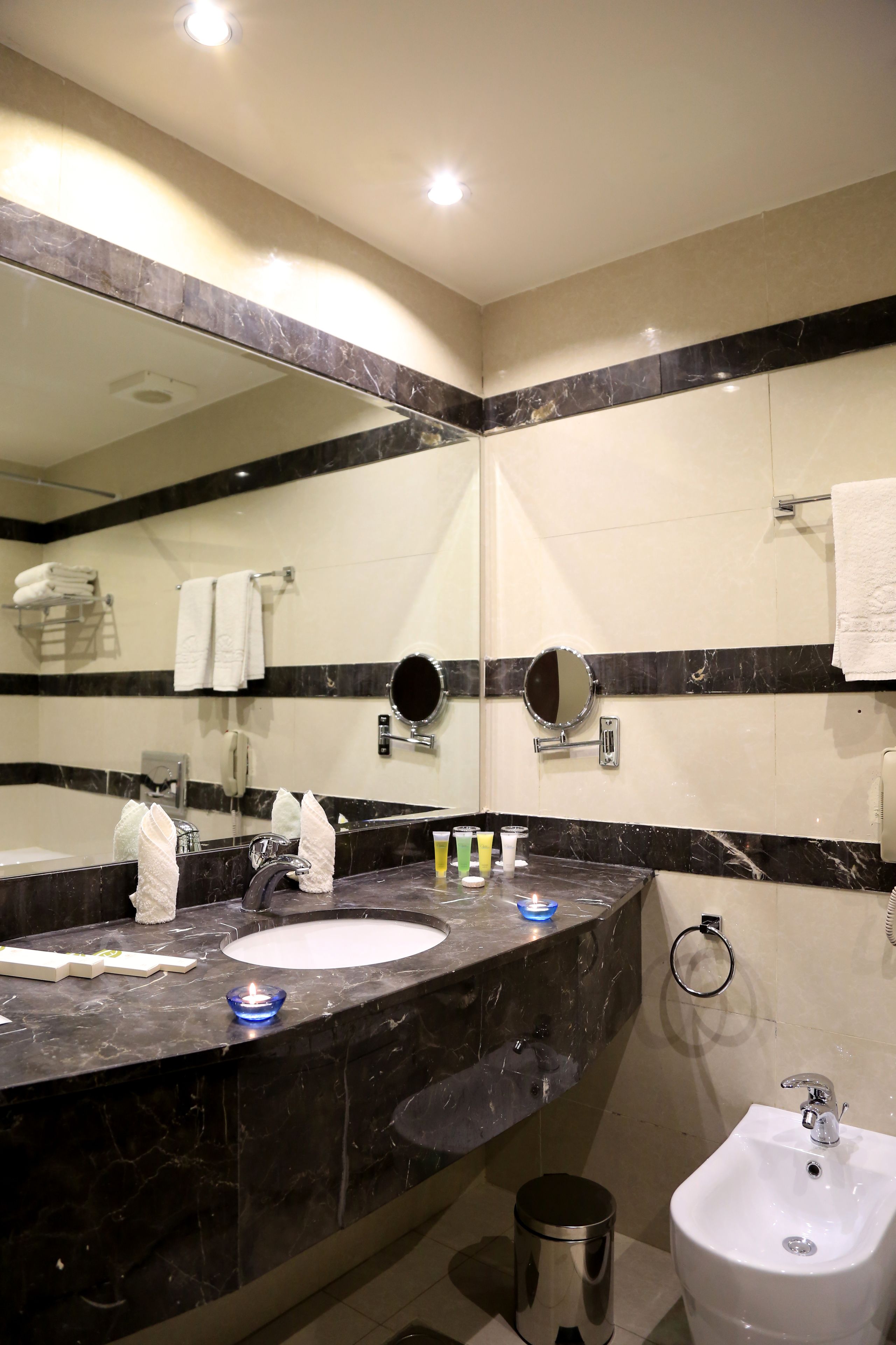 A modern bathroom with two sinks, a large mirror, and a bidet.