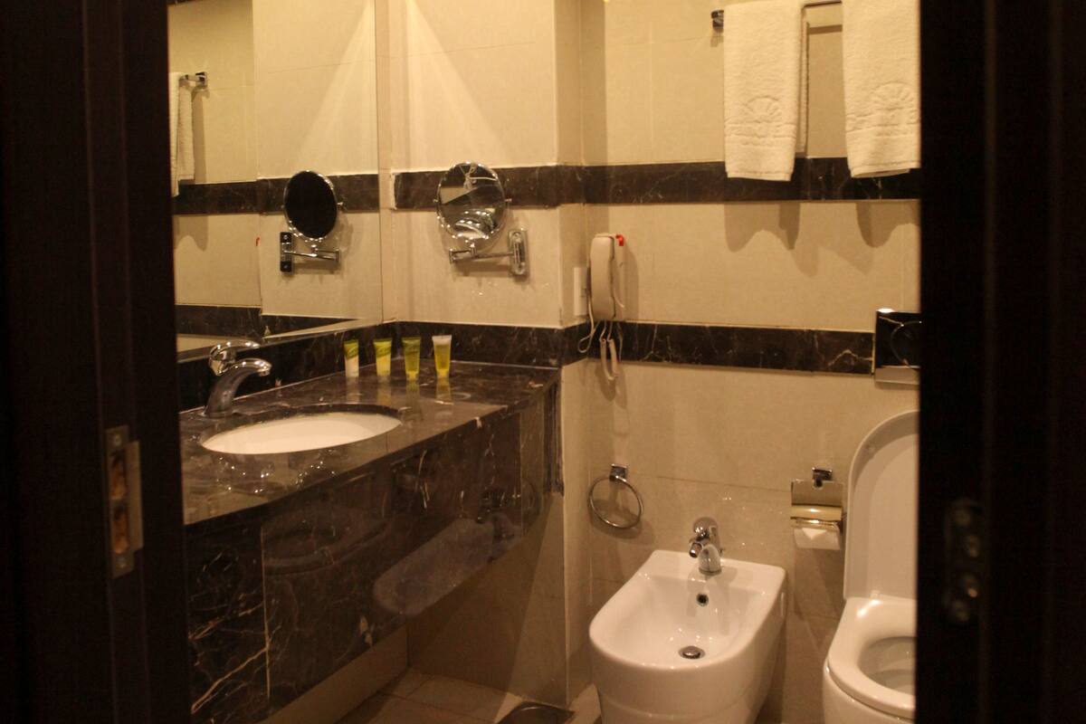 Een moderne badkamer met een marmeren wastafel, toilet en bidet.