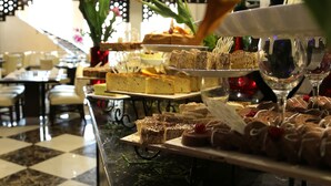 Un bufé con diversos postres y una copa de vino.