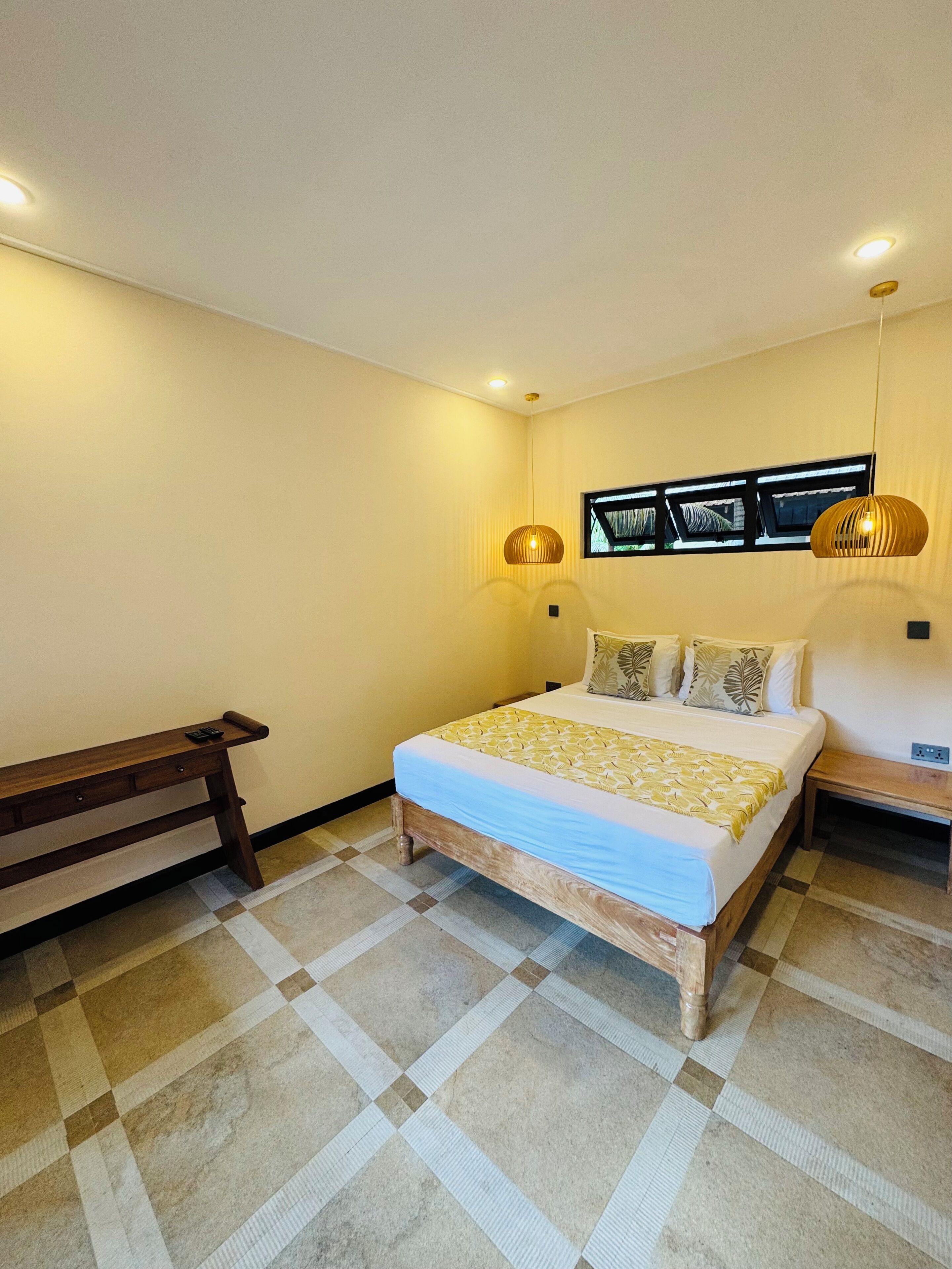 A bedroom with a bed, bedside tables, a bench, and a patterned floor.