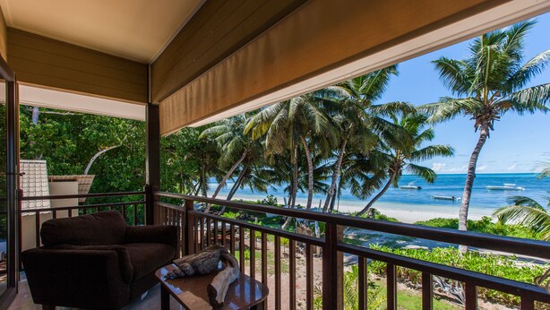 A balcony with a view of the beach, palm trees, and ocean. - Villas des Alizes (Praslin Island)
