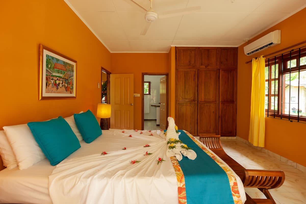 A hotel room with a bed, wooden wardrobe, and a painting on the wall.