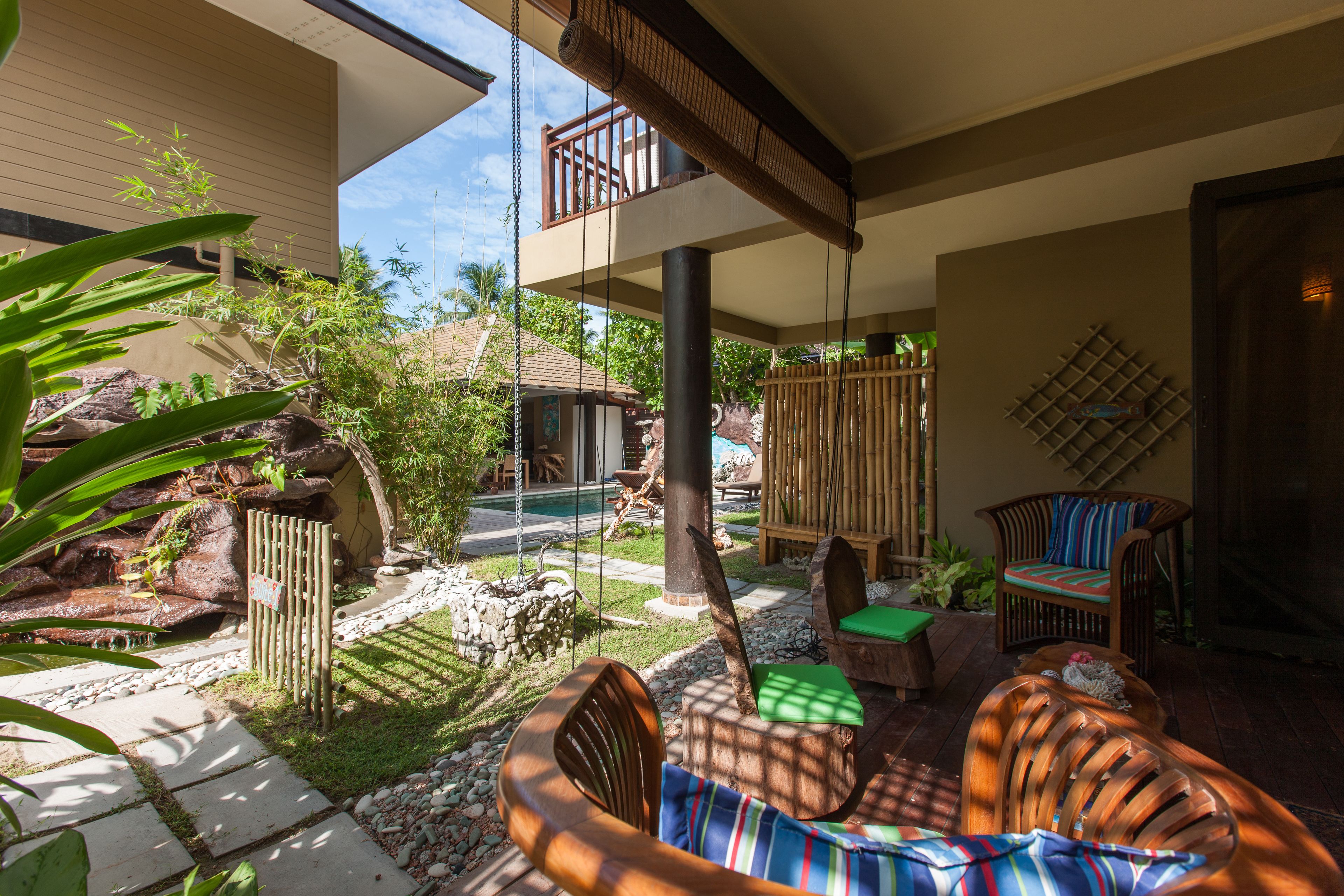 A patio area with a swing, wooden furniture, and a pool in the background.