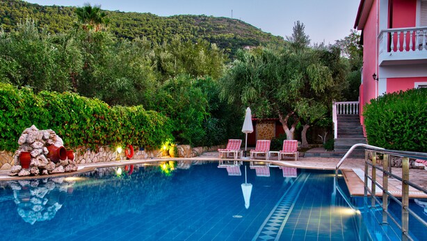 A swimming pool with lounge chairs and a stone wall. - Kyprianos (Zakynthos)