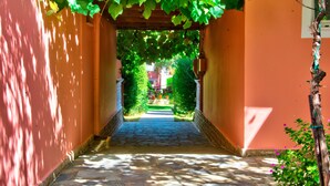A stone pathway leading through a covered area with a pergola overhead. - Kyprianos (Zakynthos)