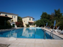 Una piscina al aire libre de temporada, sombrillas