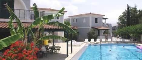 Una piscina al aire libre, sombrillas, sillones reclinables de piscina