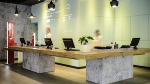 Zona de recepción con diseño moderno, que incluye un mostrador de recepción, una pantalla digital mostrando información y un reloj en la pared.