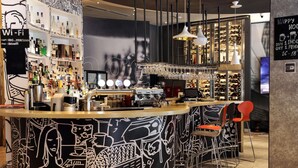 Zona de bar con mostrador circular, estanterías con botellas y un cartel de Wi-Fi.