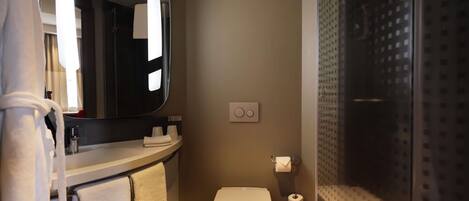 Un baño moderno con inodoro, lavamanos con espejo y cabina de ducha.