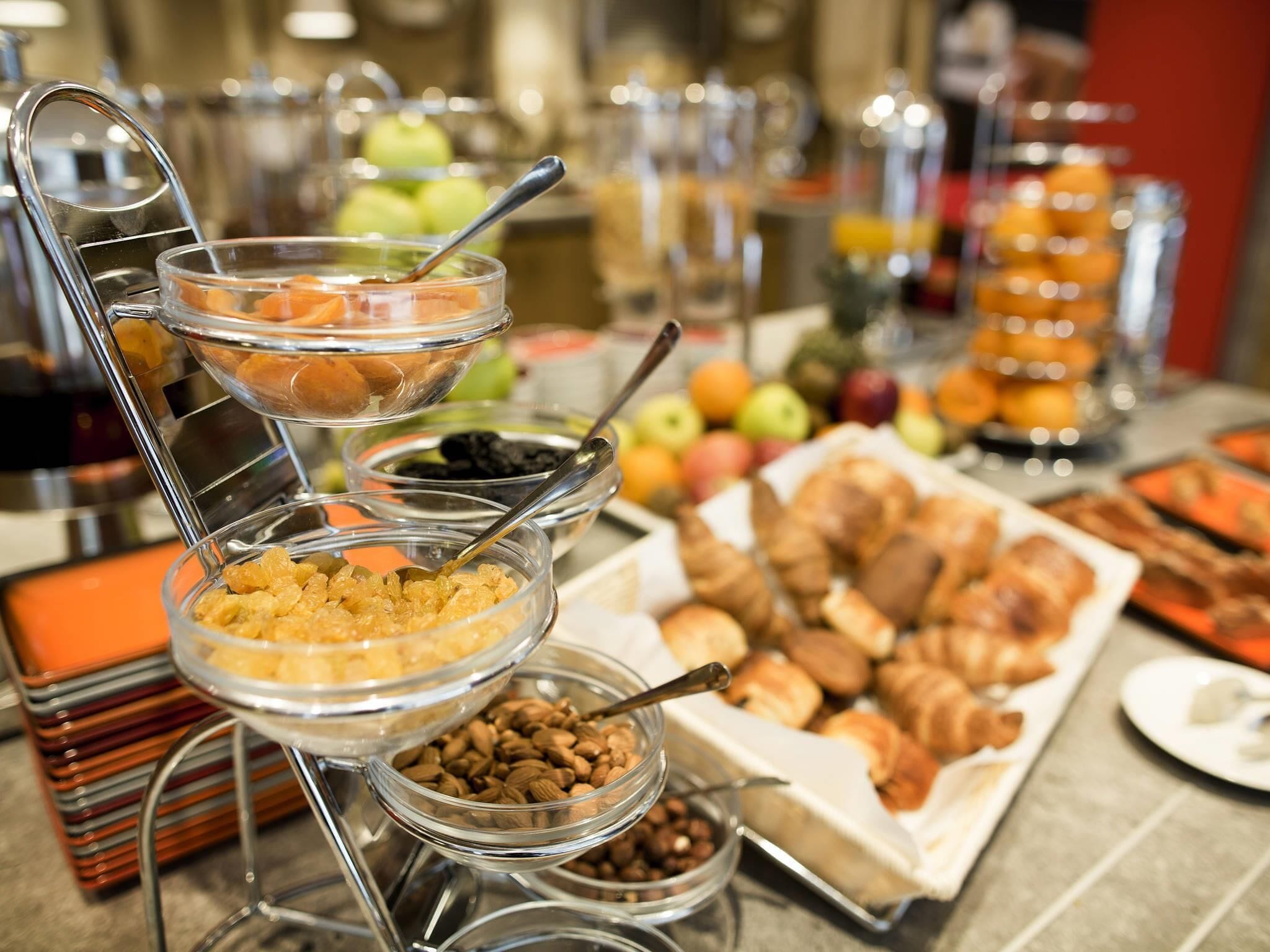 A buffet with various food items including fruits, pastries, and cereals.