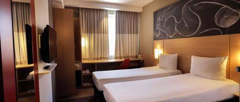 A hotel room with two beds, a desk with a chair, a television, and a large abstract painting on the wall.