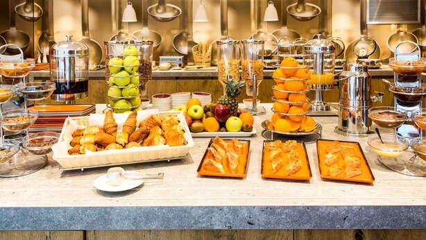 Un bufé con diversos alimentos, entre ellos frutas, pasteles y bebidas.
