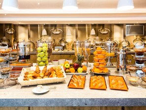 Un bufé con diversos alimentos, entre ellos frutas, pasteles y bebidas.