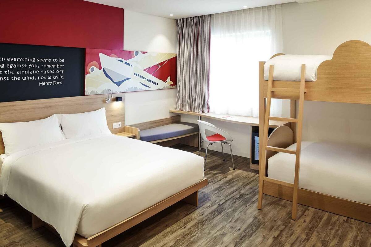 Una habitación de hotel con literas, un escritorio, una silla y una cama.