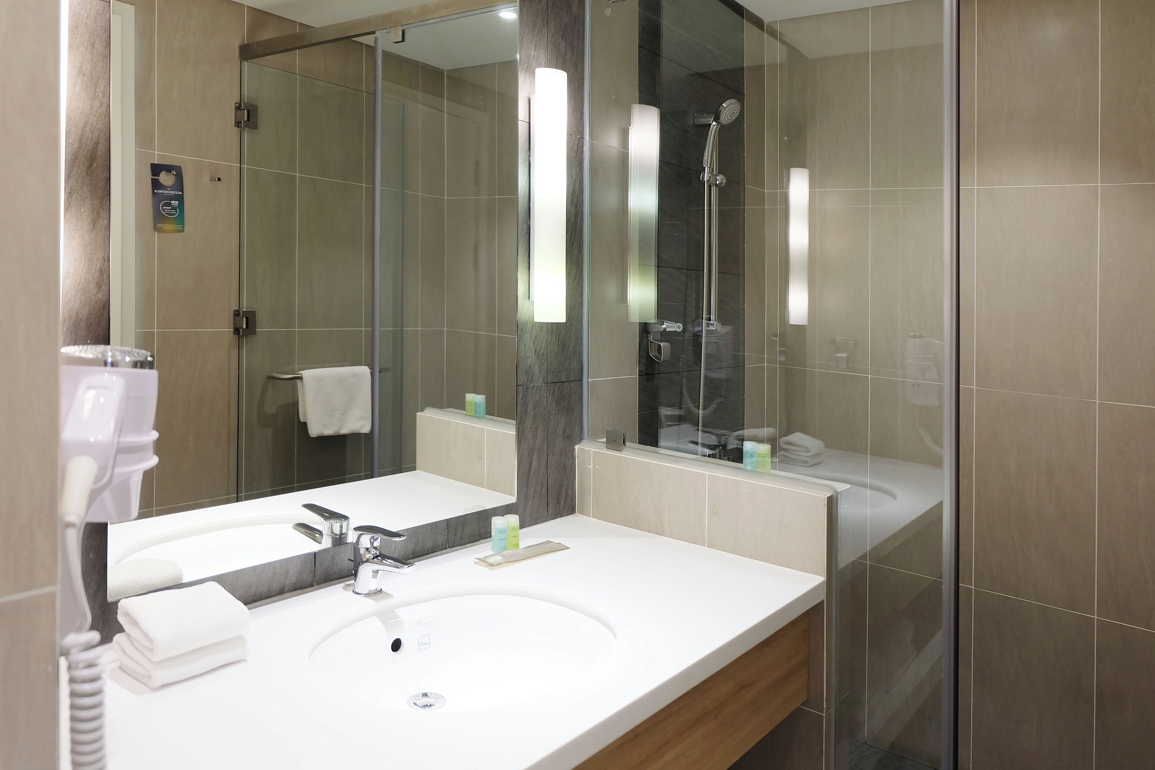 A modern bathroom with a large mirror, a sink, and a shower.