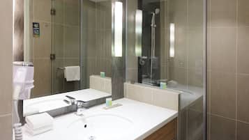 A modern bathroom with a large mirror, a sink, and a shower.