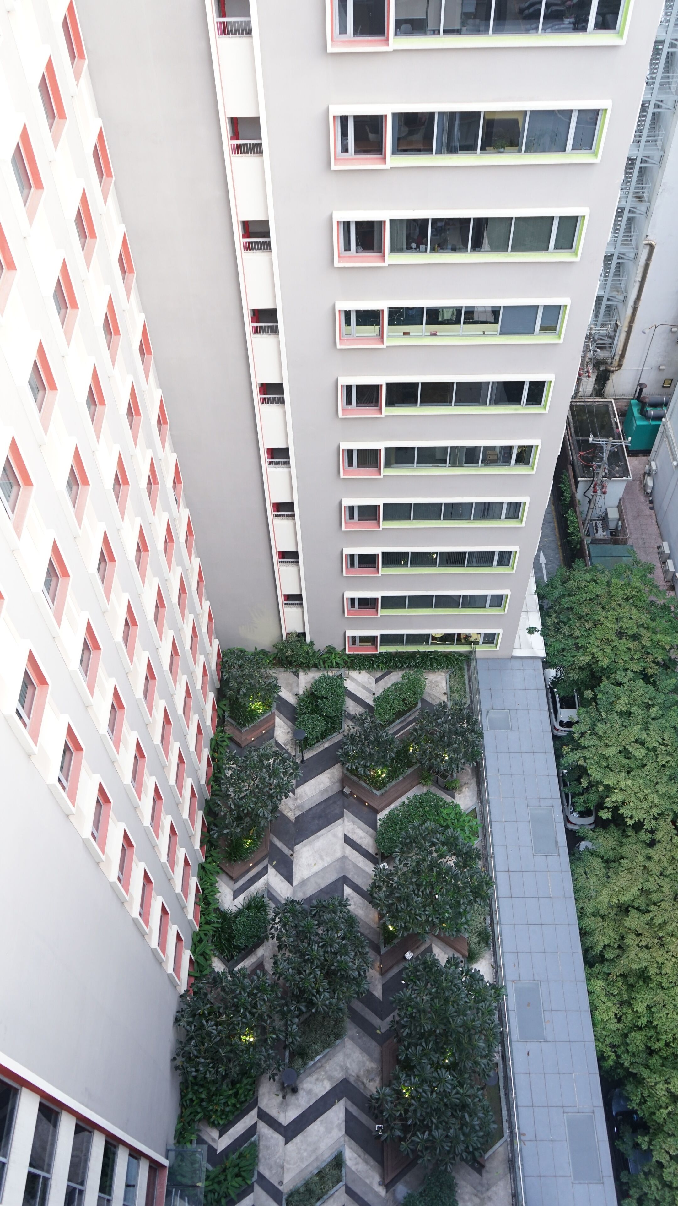 Un edificio de varios pisos con un jardín de diseño irregular y una serie de balcones.