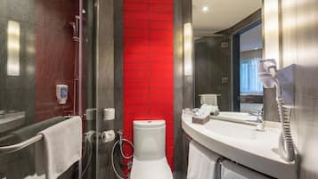 A modern bathroom with a glass shower enclosure, a white toilet, a sink with a mirror, and a red accent wall.