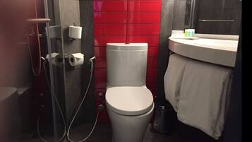 A bathroom with a toilet, a shower, and a sink.