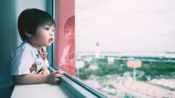 A child looking out of a window with a view of a cityscape.