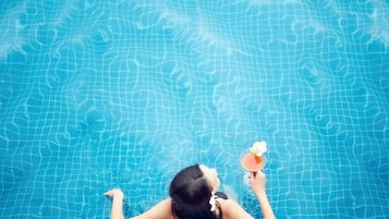 A person relaxing in a swimming pool with a drink.