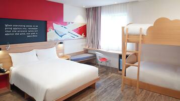 A modern hotel room with a large bed, a desk, a bunk bed, and a motivational quote on the wall.