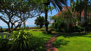 A lush garden with a red pathway leading to a building with a red roof. - Chomtalay Resort at Had Chaosamran Beach (Ban Laem)