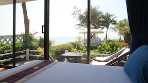 A bedroom with a bed, a view of the sea, and a balcony with plants and a table. - Chomtalay Resort at Had Chaosamran Beach (Ban Laem)