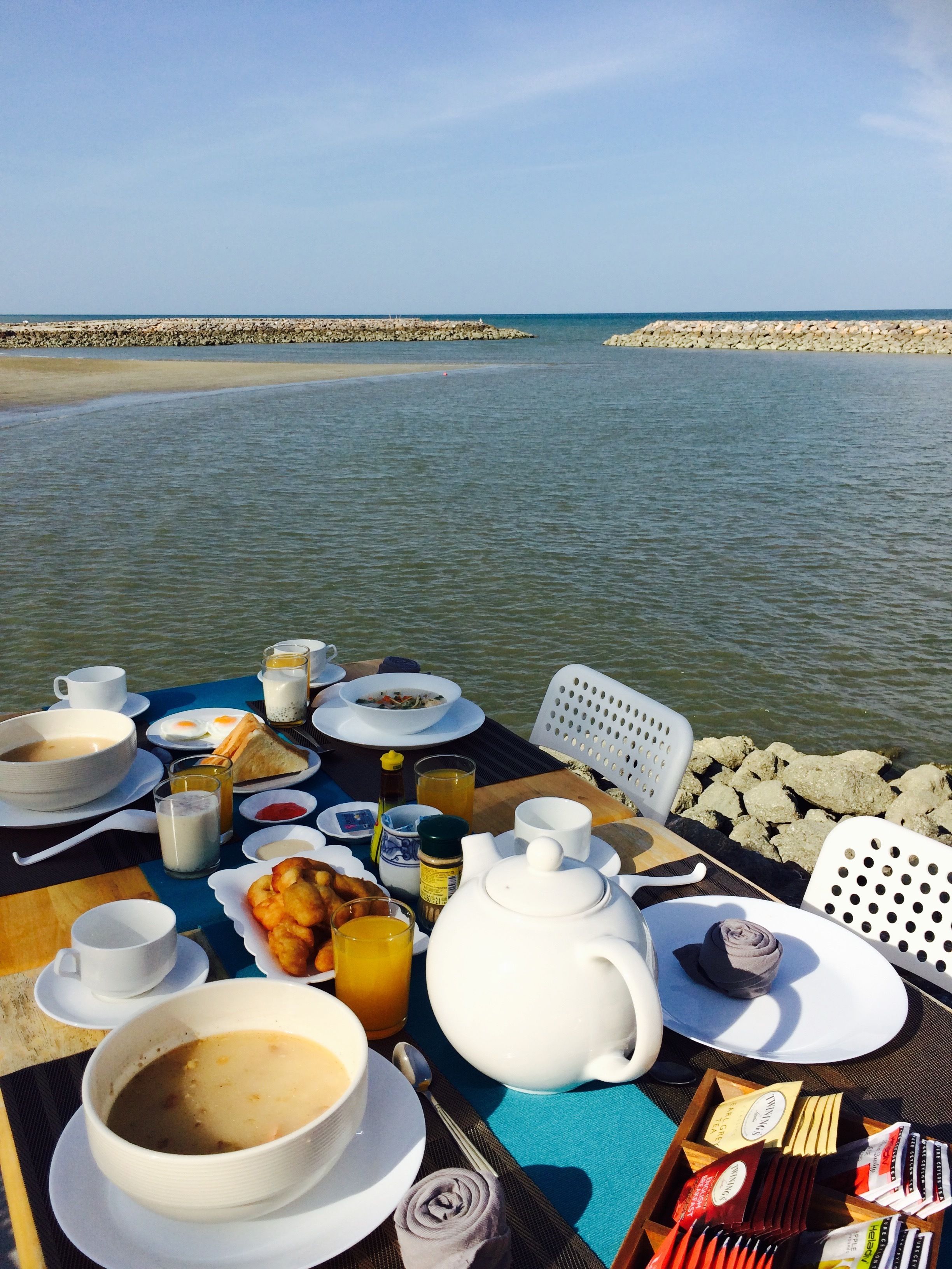 Une table dressée pour le petit-déjeuner, placée près d’une côte rocheuse, avec vue sur la mer.