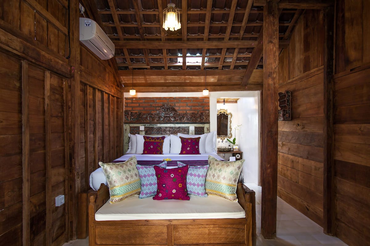 Une chambre dans une cabane en bois, avec un lit, des oreillers et un ventilateur de plafond.