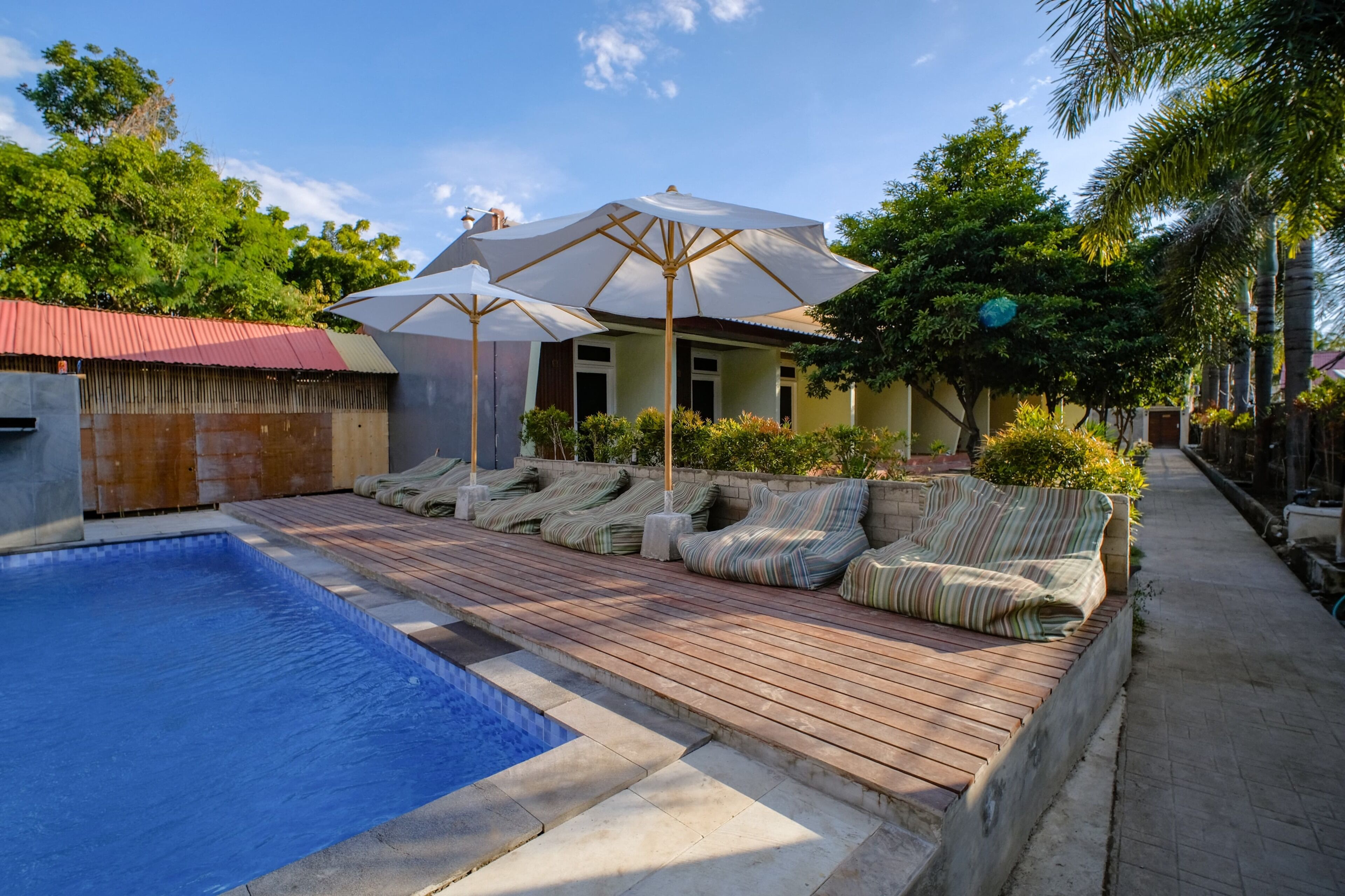 A swimming pool with a wooden deck, lounge chairs, and umbrellas.