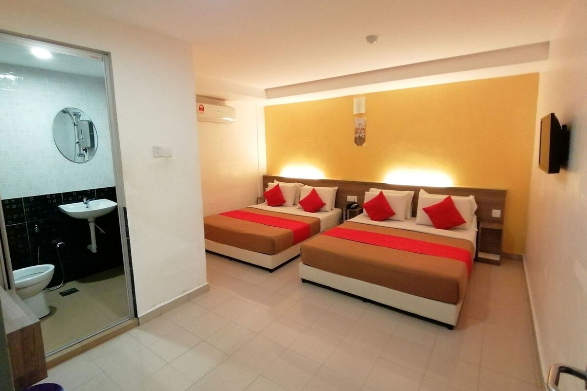 A hotel room with two beds, a bathroom, and a TV.