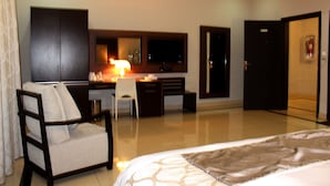 Una habitación de hotel con cama, escritorio, silla, televisor y armario.