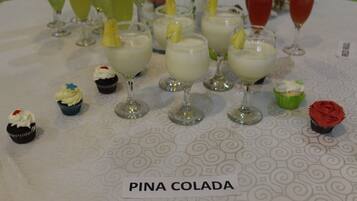 A table with various desserts and drinks, including cupcakes and glasses of a creamy beverage, labeled "PINA COLADA".